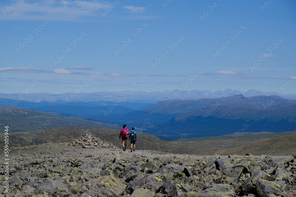 Fototapeta premium Scenic Besseggen trail in Jotunheimen, Norway - the most beautiful trekking trail in Norway. Silhouettes of hiking tourists on trail.