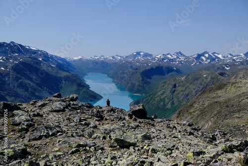 Scenic Besseggen trail with man sitting on viewpoint, in Jotunheimen, Norway - the most beautiful trekking trail in Norway. Silhouette of man sitting on viewpoint photo