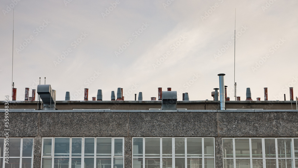 the roof of a building with a large number of ventilation pipes on a gray sky background