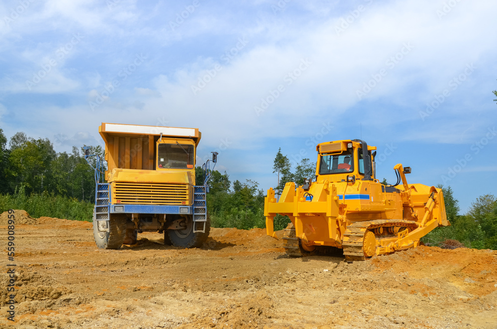 Crawler dozer working on construction site or quarry. Mining machinery moving clay, smoothing gravel surface for new road. Earthmoving, excavations, digging on soils