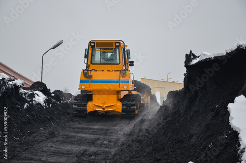 Crawler bulldozer working on a coal heap. Mining machines moving clay, smoothing the surface of gravel for a new road. Earthworks, excavations, digging in the soil