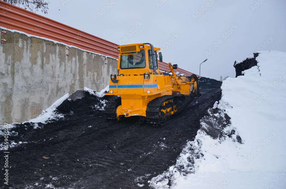 Crawler bulldozer working on a coal heap. Mining machines moving clay, smoothing the surface of gravel for a new road. Earthworks, excavations, digging in the soil Crawler bulldozer working on a coal heap. Mining machines moving clay, smoothing the surface of gravel for a new road. Earthworks, excavations, digging in the soil