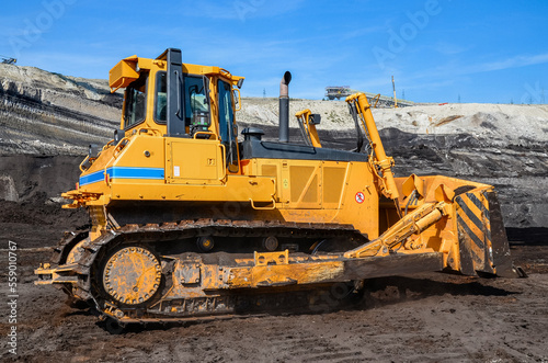 Crawler bulldozer working on construction site or quarry. Mining machinery moving clay, smoothing gravel surface for new road. Earthmoving, excavations, digging on soils