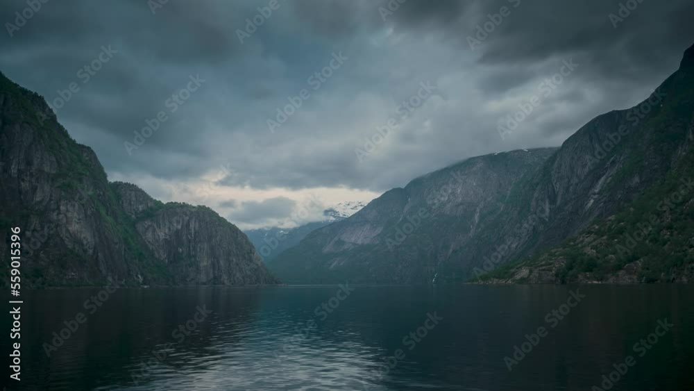 Timelapse video of sunset with last sunbeams in the fjord and mountain landscape Eidfjord in Norway, moving clouds in the sky and surface of water