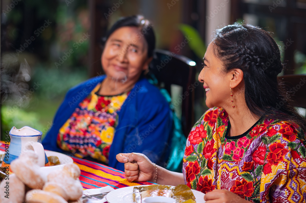 Fototapeta premium Mother and daughter spending time together. Eating Tamale, a traditional Guatemalan dish.