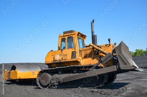 Crawler bulldozer with a large roller for compaction on a coal heap. 