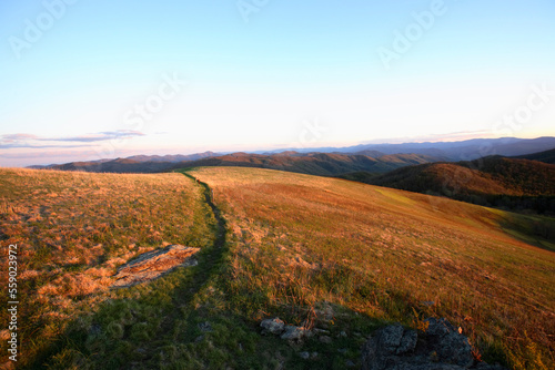 View down the final stretch of the Appalachian Trail to the summit of Max Patch Bald west of Asheville, NC at sunset.
