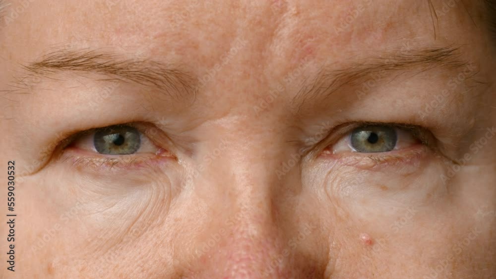Close-up view of an elderly woman. the woman opens her eyes and looks into the camera. The skin of an elderly person. Senior woman eyes, wrinkled face