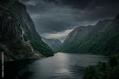 Moody fjord with mountains and waterfall of Aurlandsfjord at Gudvangen in Norway  dark clouds in the sky  from above