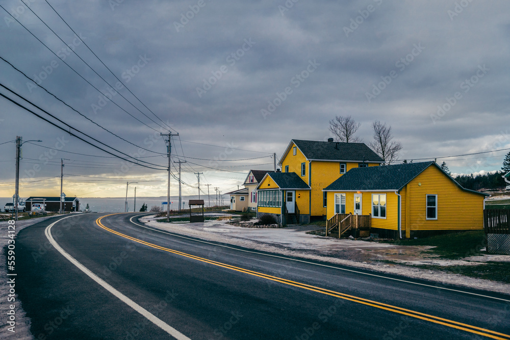 driving on a road next to a yellow house in a snowy landscape