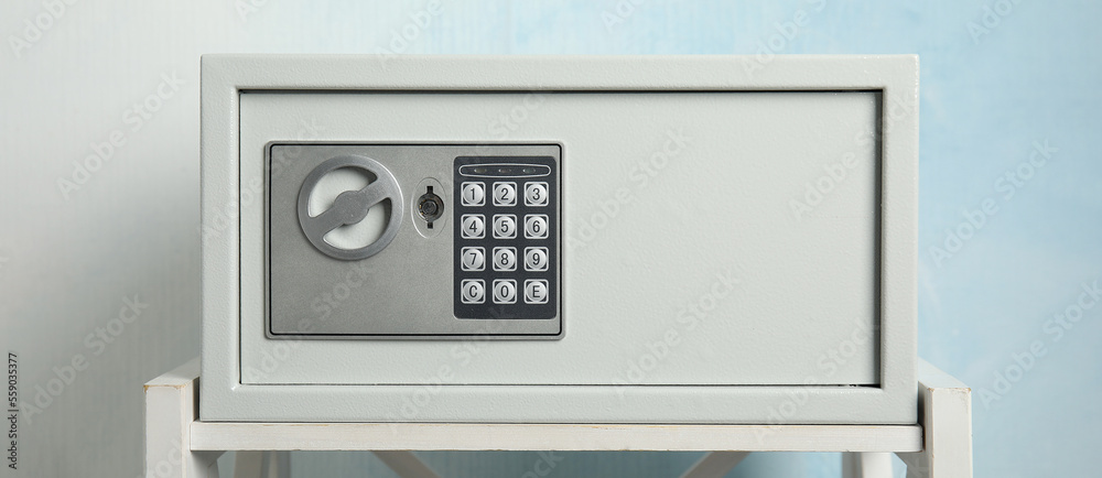 Closed steel safe on white table against light blue background, banner design Closed steel safe on white table against light blue background, banner design