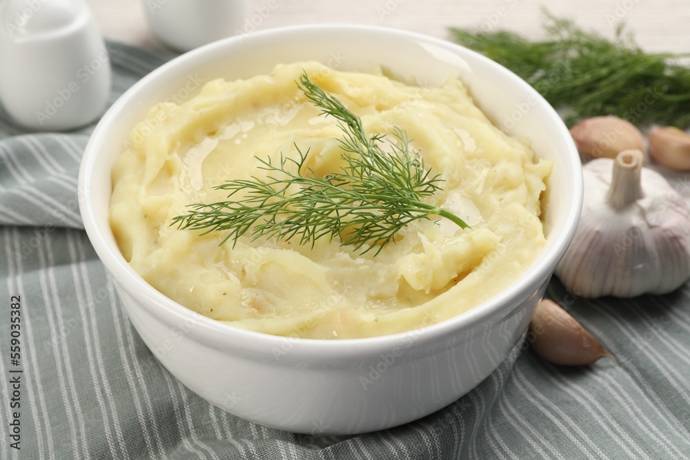 Bowl of tasty mashed potato with garlic and dill on table, closeup