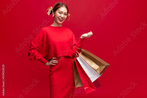 Young asian woman wearing red sweater dress with shopping bags on red background for Chinese new year and Christmas festival