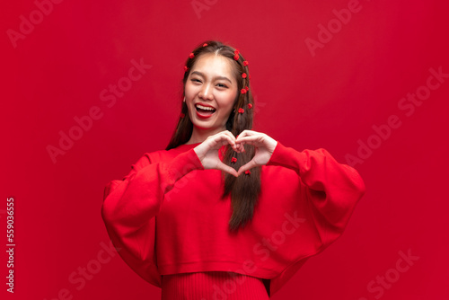Fotobehang Young asian woman wearing red sweater dress shapes heart gesture on red backgrou