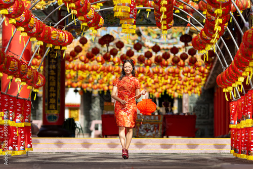 Asian woman in red cheongsam qipao dress holding lantern while visiting the Chinese Buddhist temple during lunar new year for traditional culture concept © Akarawut