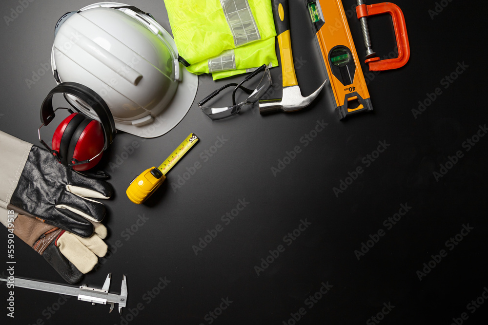 Work safety. Construction site protective equipment on wooden background, flat lay, copy space, top view Work safety. Construction site protective equipment on wooden background, flat lay, copy space, top view