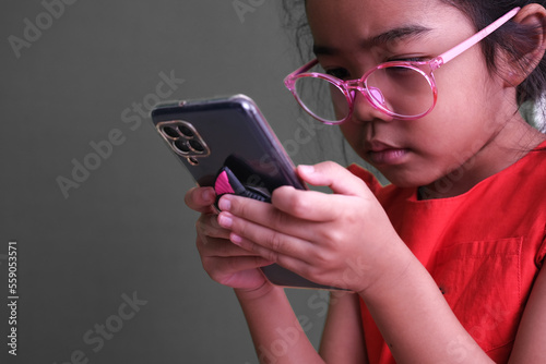 Little girl in red, sitting and busy playing with her gadget photo