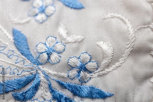 Macro abstract texture background of a blue and white needlepoint crafted flower pattern on white cloth photo