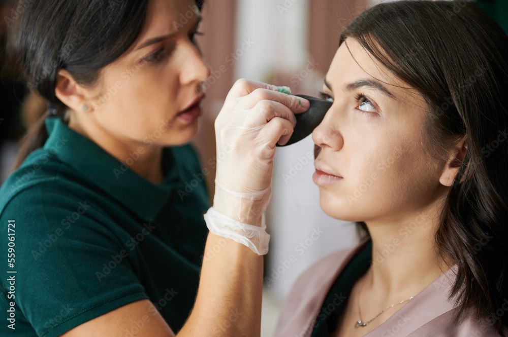 Close up of female beauty specialist using blending sponge while applying foundation under woman eye. Professional makeup artist doing makeup for client in visage studio. Close up of female beauty specialist using blending sponge while applying foundation under woman eye. Professional makeup artist doing makeup for client in visage studio.