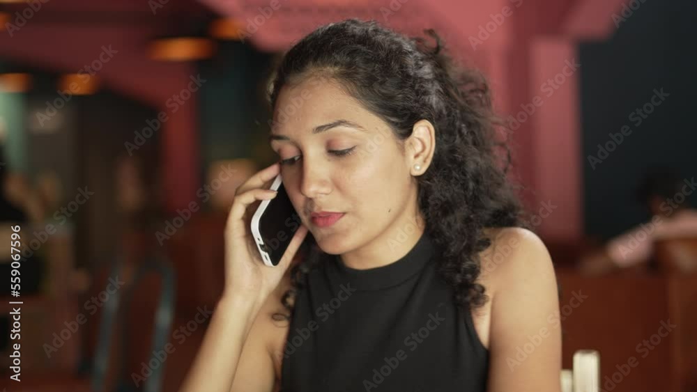 close-up young Indian business woman talking on smartphone with colleague or client standing alone at cafe. Distance phone call to solve business, enjoy personal conversation, make order concept