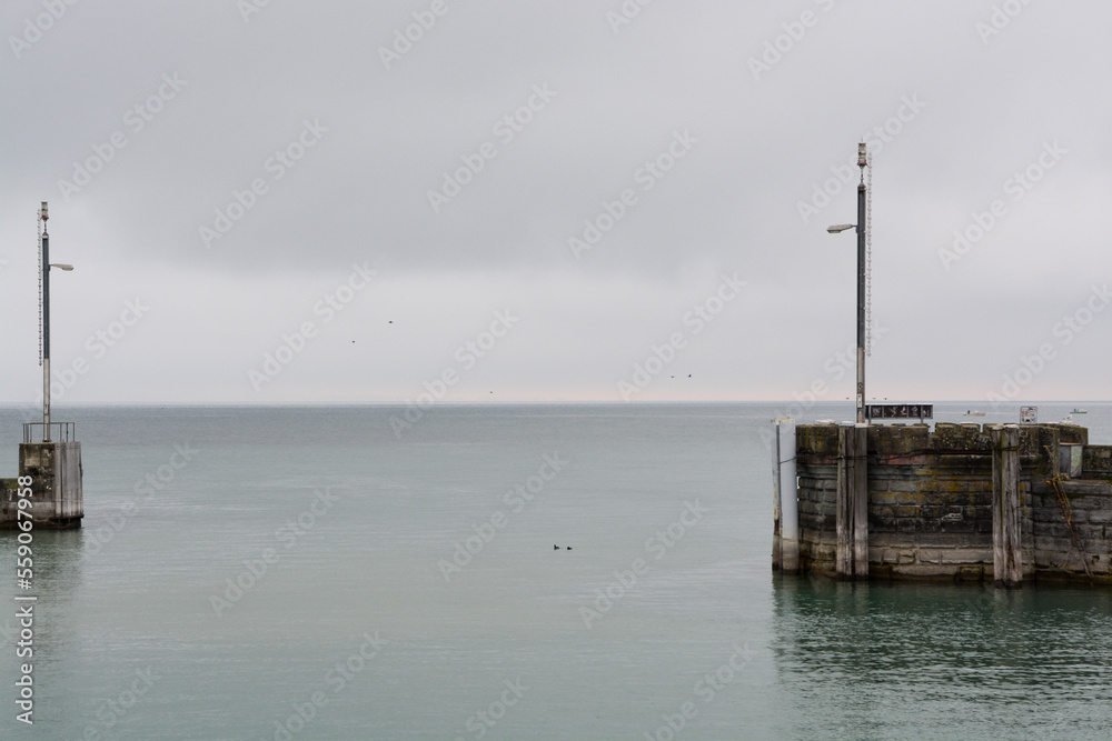 View over lake to horizon through harbour mole and exit of harbour on a cloudy day in fall, Romanshorn, Lake Constance, Bodensee, Switzerland