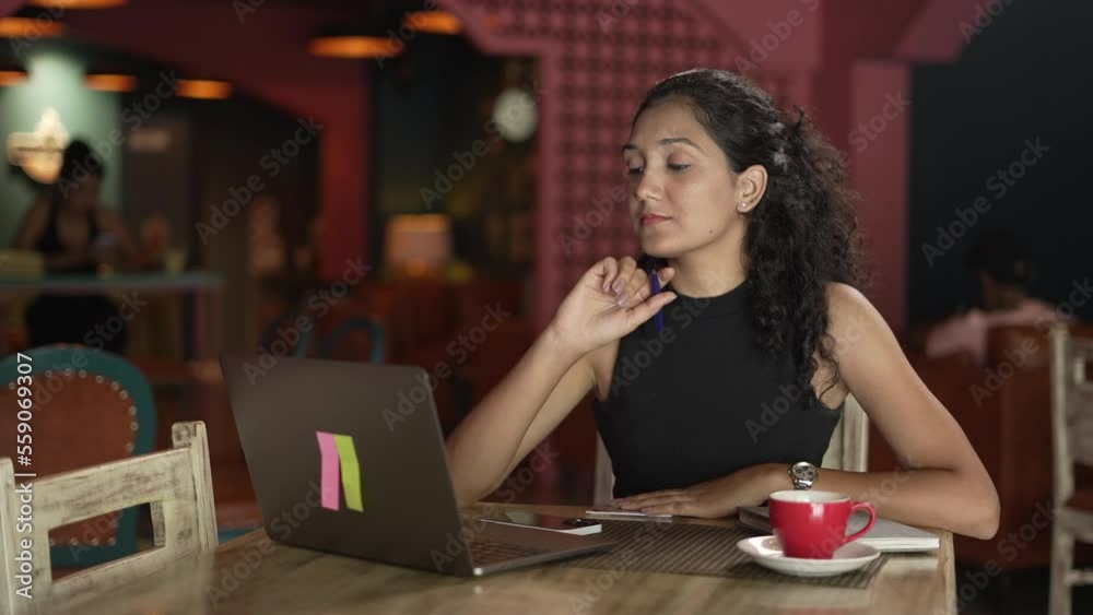 Close-up Indian young business woman siting at table in the restaurant.Portrait of positive Asian business woman working on laptop computer while drinking coffee.and looking at laptop screen indoors. Close-up Indian young business woman siting at table in the restaurant.Portrait of positive Asian business woman working on laptop computer while drinking coffee.and looking at laptop screen indoors.