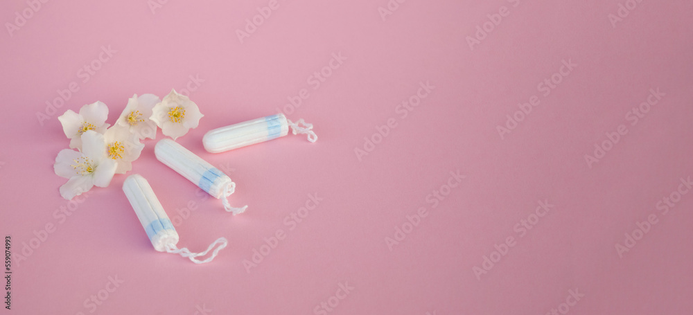 The concept of careful and gentle protection in critical days. Menstruation period concept. Hygienic white tampons for women with flowers jasmine on pink backround.