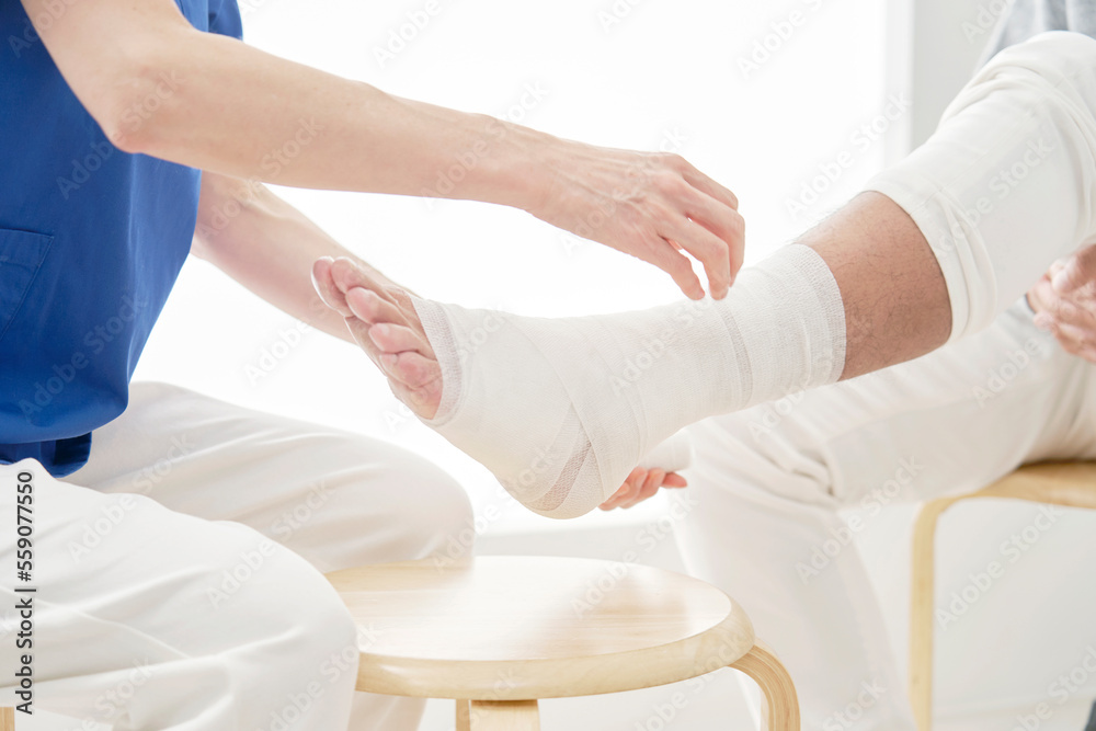 Fototapeta premium 足に包帯を巻く医師 顔無し