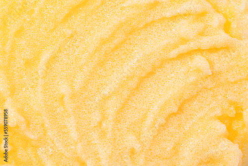 Sugar or salt body scrub texture. Yellow scrub - skin care product with fruit extract as cosmetic background with copy space. Macro photo