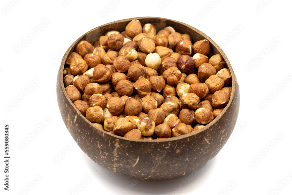Roasted hazelnuts isolated on white background. Nuts in a coconut bowl. Studio shoot. close up Roasted hazelnuts isolated on white background. Nuts in a coconut bowl. Studio shoot. close up