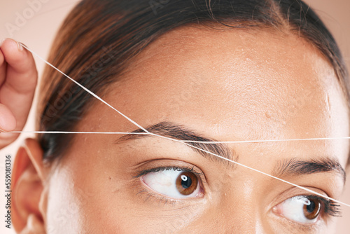 Threading, eyebrows and beauty with a model black woman in studio on a beige background for hair removal. Eyes, zoom and wellness with an attractive young female using a product on her face