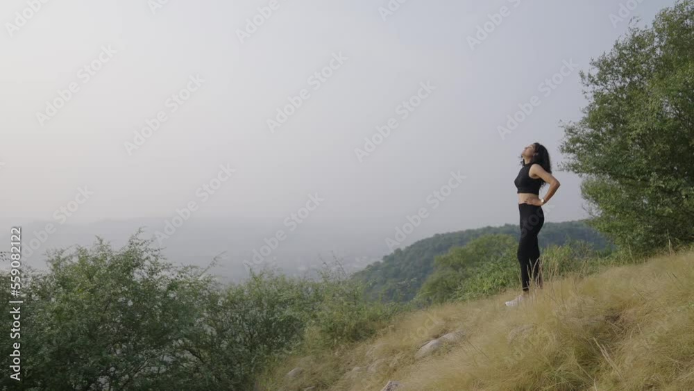 young Indian women clamber up on the top of mountain in the morning. Asian young girl clime hiking and tiredness standing with look at the beautiful morning view on the top of mountain. young Indian women clamber up on the top of mountain in the morning. Asian young girl clime hiking and tiredness standing with look at the beautiful morning view on the top of mountain.