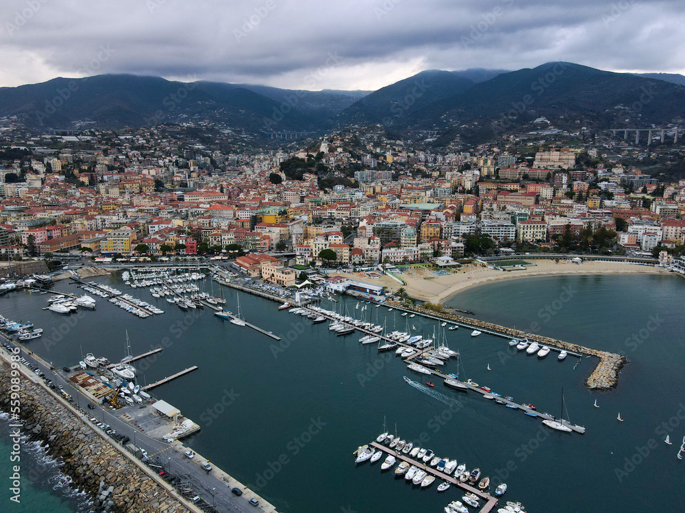 Aerial view of Sanremo, Italian city on the seashore in Liguria, north Italy. Drone flying along the port over beaches and boardwalk with palm trees and Birds Eye of yacht parking in San Remo, Italy.