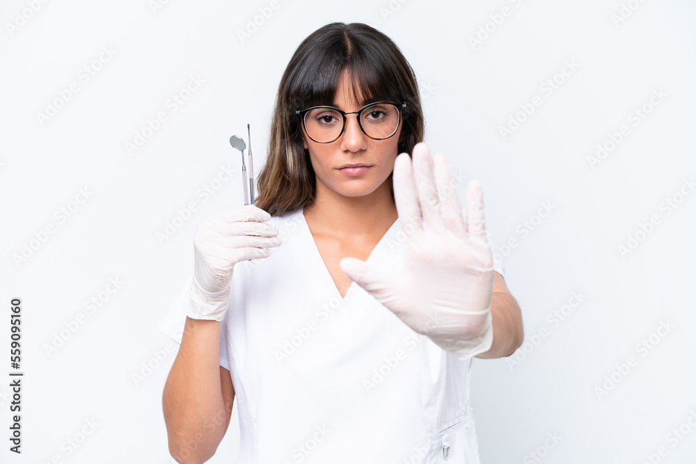 Dentist caucasian woman holding tools isolated on white background making stop gesture Dentist caucasian woman holding tools isolated on white background making stop gesture