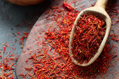 Fototapeta Naklejka Na Ścianę i Meble -  Heap of dried saffron spice in spoon on rustic background, spices and herbs concept (Crocus sativus)