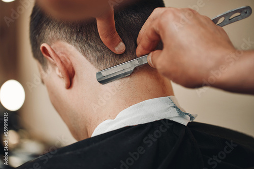 Fotografia Barber shaving bearded man with retro knife