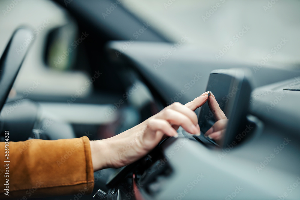 Close up of a female's hand entering coordinates on gps in car.