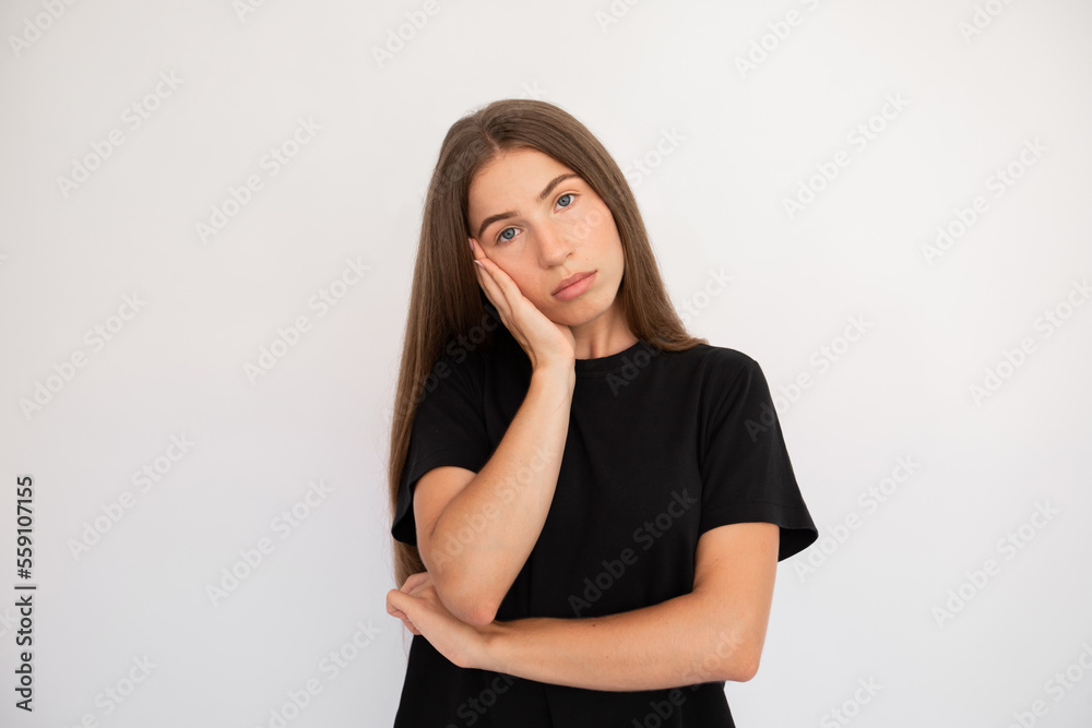 Portrait of bored young woman looking at camera over white background. Caucasian lady wearing black T-shirt leaning head on hand with tired expression. Boredom concept Portrait of bored young woman looking at camera over white background. Caucasian lady wearing black T-shirt leaning head on hand with tired expression. Boredom concept