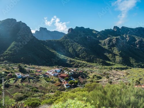 Dramatic lush green picturesque valley with old village Los Carrizales . Landscape with sharp rock formation, hills and cliffs seen from mountain road, Tenerife, Canary Islands, Spain. sunny winter