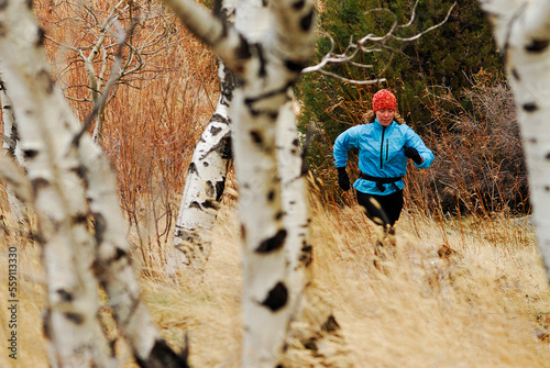 A woman trail running near birch trees. photo