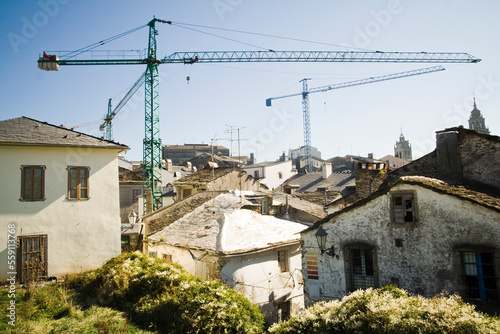 Giant construction cranes loom over the old slate rooftops of Lugo, Galicia, Spain. photo