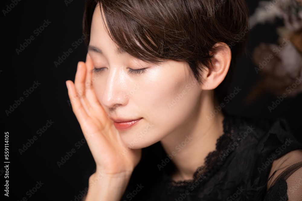 目を閉じてお肌を気にする女性 黒バック 目を閉じてお肌を気にする女性 黒バック