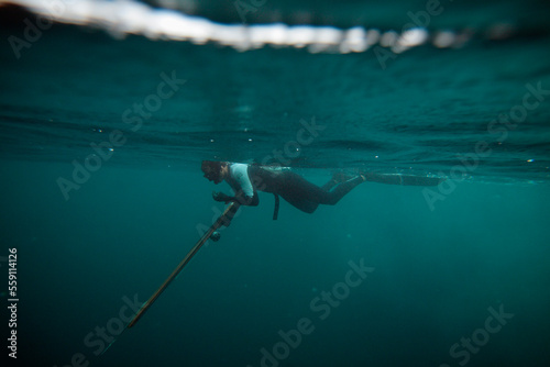 A freediver prepares his speargun at surface before a dive. photo