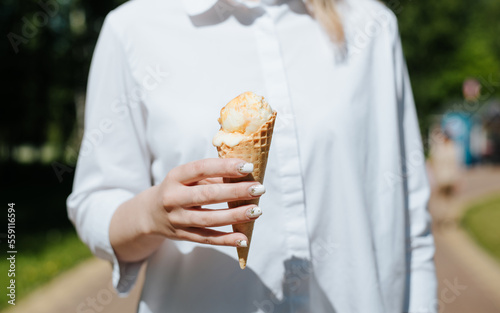 Close-up of woman s hand holding an ice cream waffle cone on sunny day outdoors  front view