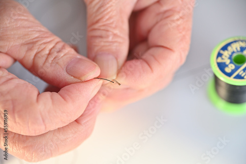 針に糸を通す高齢女性の指先 photo