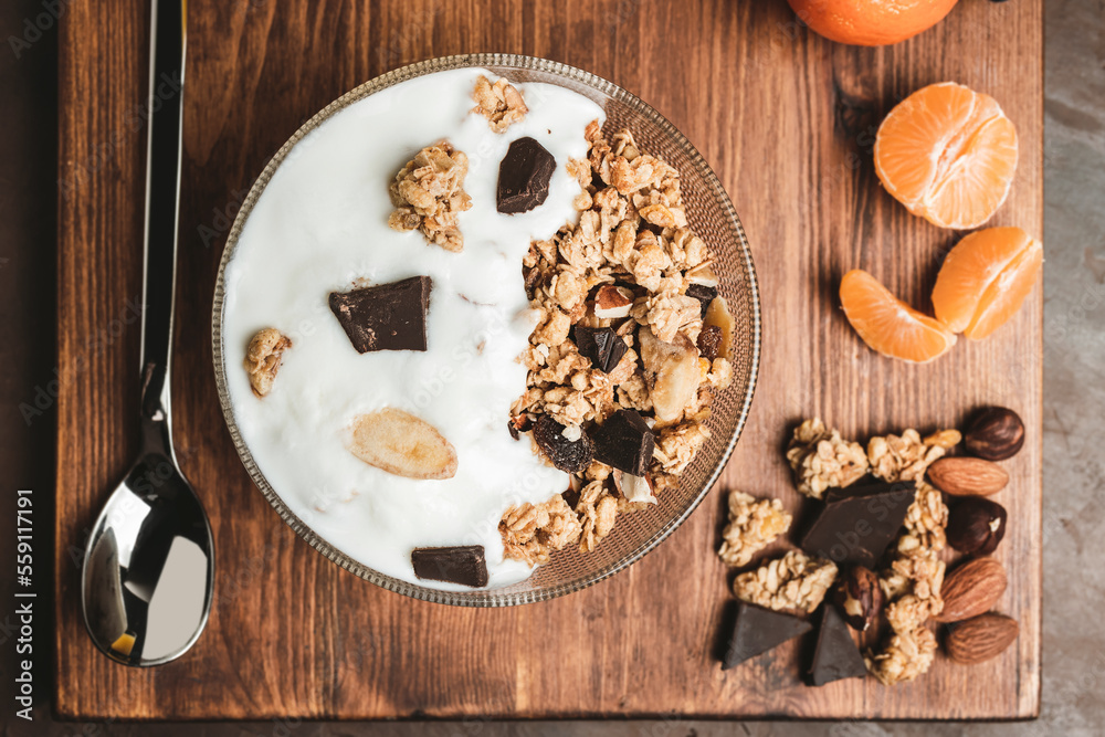 Granola cereal oatmeal with white yogurt, chocolate, fruist and nuts in a bowl on dark wooden board, top view Granola cereal oatmeal with white yogurt, chocolate, fruist and nuts in a bowl on dark wooden board, top view