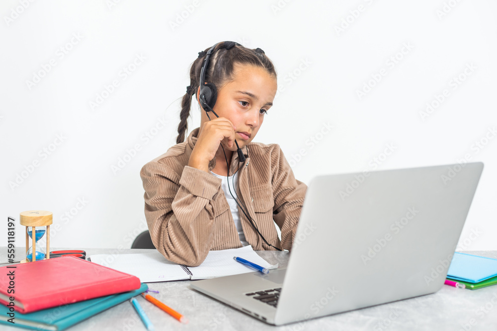 caucasian girl sitting at the desk and writing in a notebook and doing homework. caucasian girl sitting at the desk and writing in a notebook and doing homework.