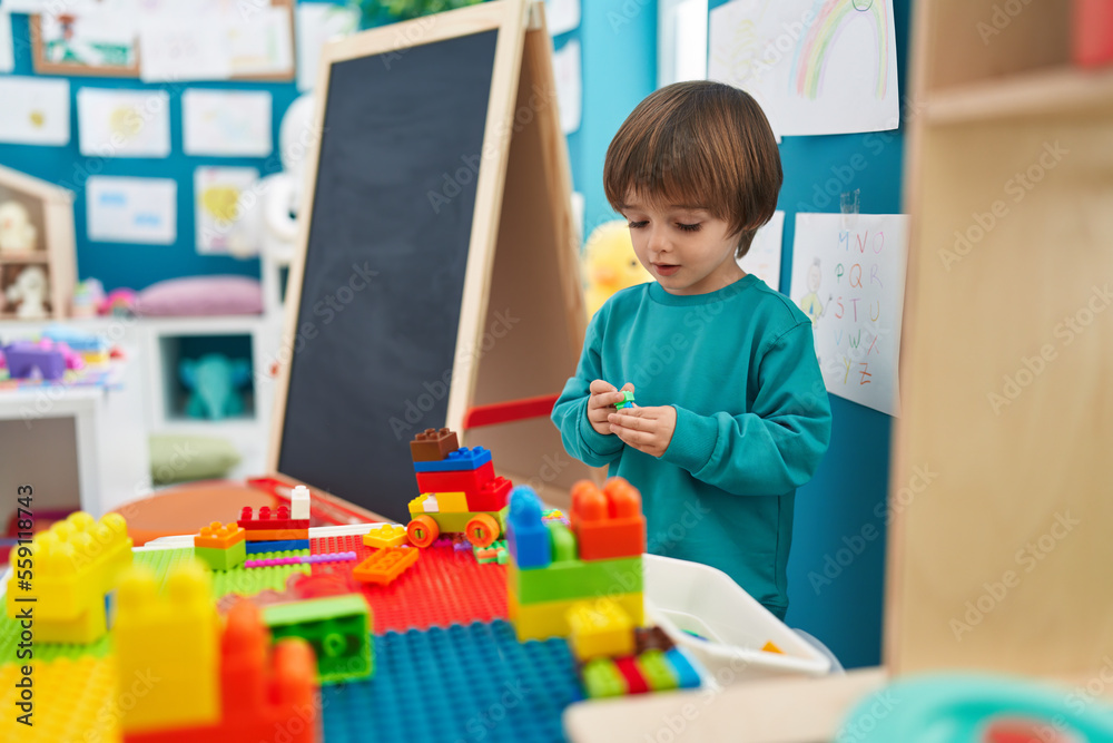Adorable toddler playing with construction blocks standing at kindergarten Adorable toddler playing with construction blocks standing at kindergarten