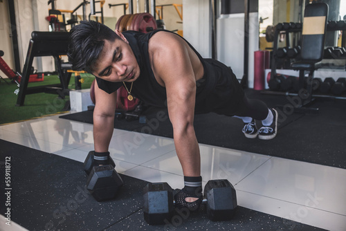 A fit and tanned man preapring to start a set of 45 degree pushups on hex dumbbells acting as a push up handle. Chest, anterior deltoid and tricep training. photo