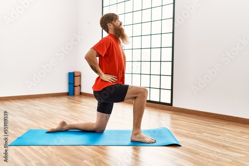 Young redhead man smiling confident stretching at sport center